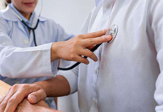 A doctor examines a patient with a stethoscope on the patient&#x2019;s chest.