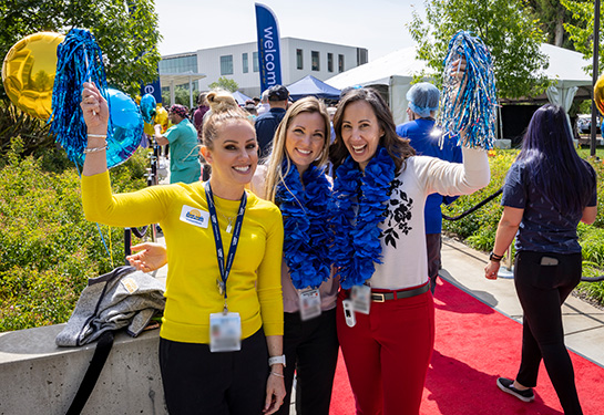 Group of three women outside holding balloons 