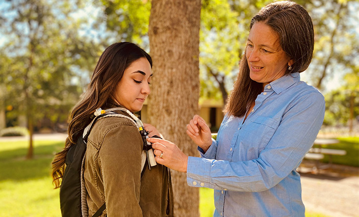 Two women stand facing each other in an outdoor setting.