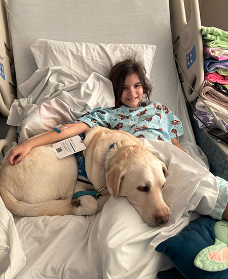 Girl patient resting in a hospital bed with a dog beside her