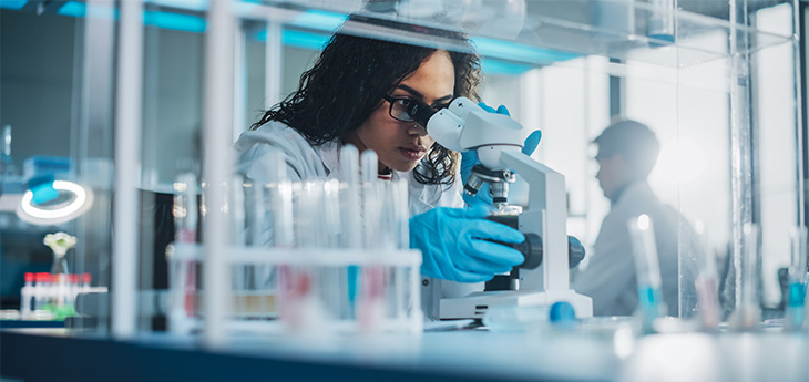 Female scientist looking through a microscope in a lab