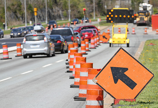 A move left sign and a digital flashing arrow with traffic cones advises cars on freeway.   