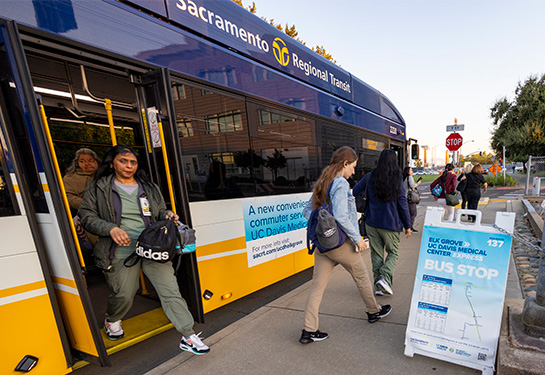 Woman exiting the back of a Sacramento Regional Transit bus as others walk away from the bus. 