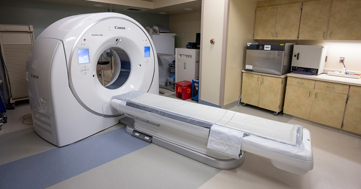 A computed tomography scanner with a large donut shaped circle of the head of a bed.