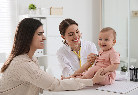 Female doctor examining baby while female looks on