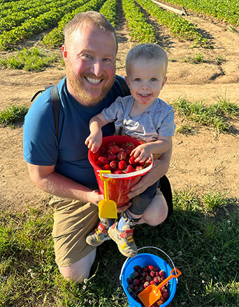 Child picking strawberries with dad