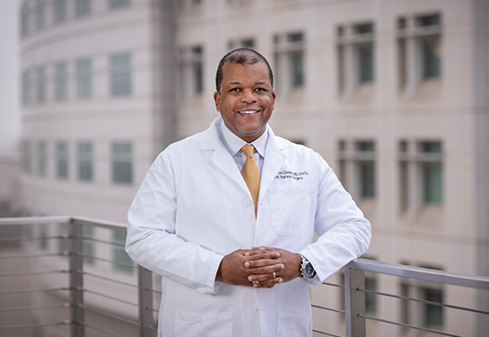 Doctor in white coat standing with hands folded