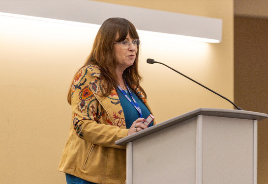 Kim Barrett stands at podium