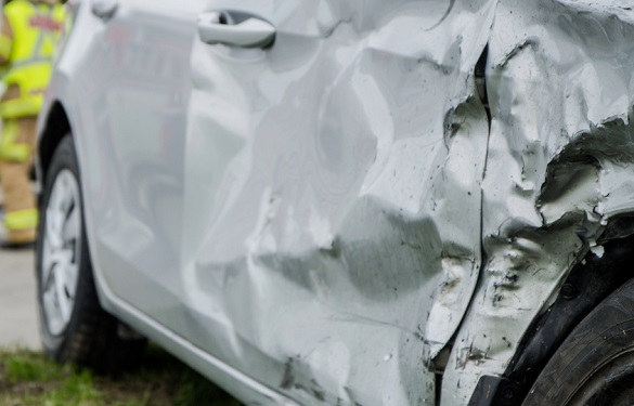 Damaged gray car with three firefighters wearing yellow jackets in the background.