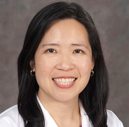 Woman in white coat smiling into camera