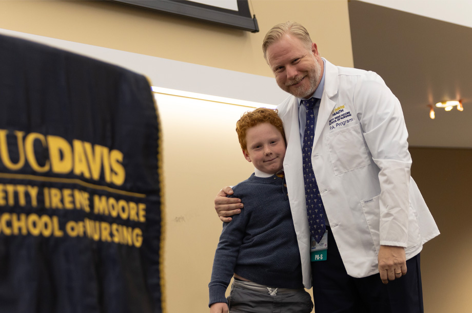 Nick Woods, right, stands with arm around his young son on stage