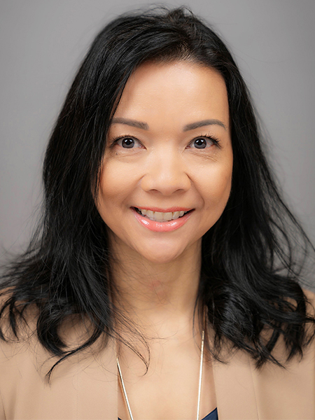 Portrait of a woman with dark hair below her shoulders and wearing a tan blazer