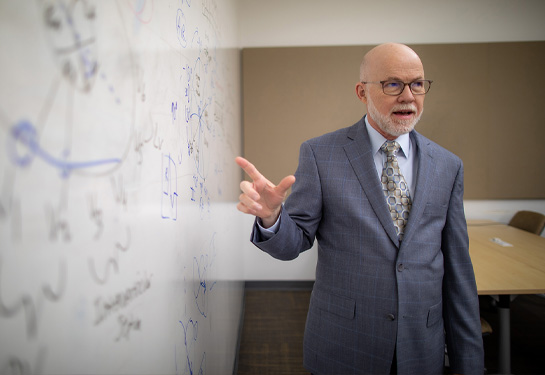 Man standing in front of classroom pointing at white board