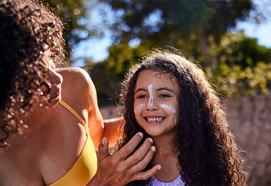 Mom putting sunscreen on a young girl