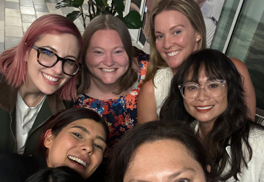 Five women in tight group smiling at camera