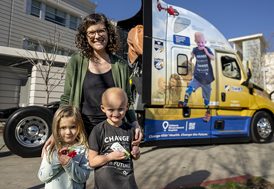 Woman with two children in front of semitruck