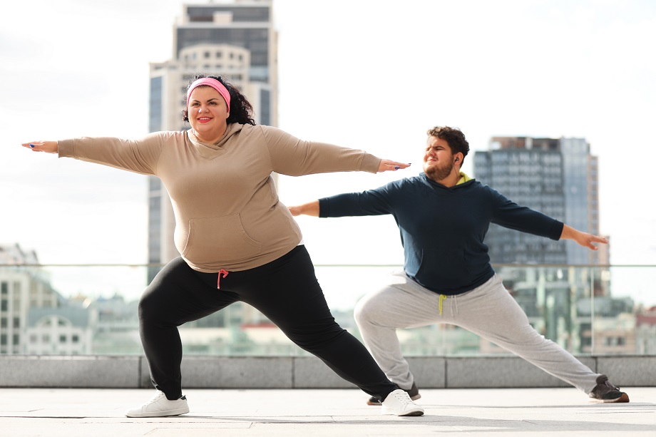 Two individuals performing a lunge on top of a building. 