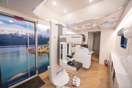 Mammography machine inside mobile unit with mural of Lake Tahoe behind it.