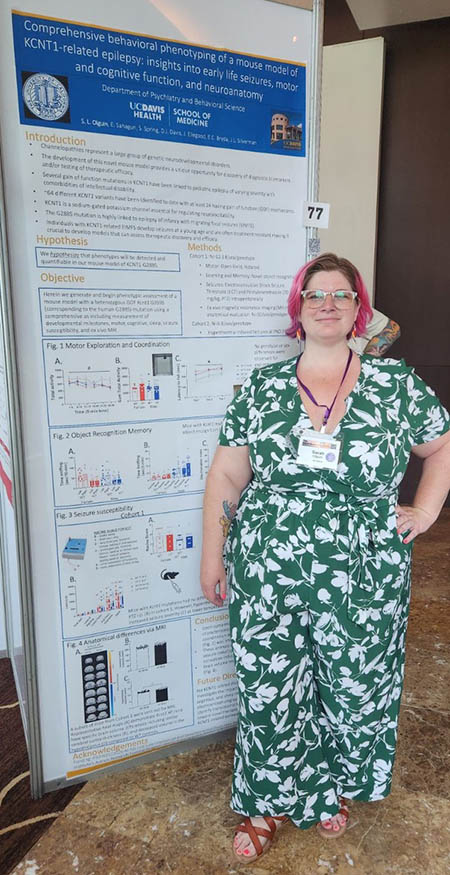 A person stands next to a research poster at an academic conference.