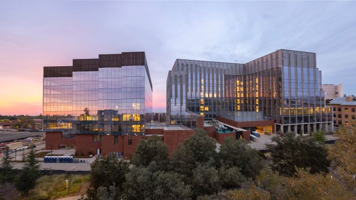 Aggie Square with the sunset in the background and reflected on its window panels