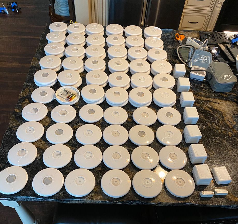 Dozens of white, circular monitors the shape of thin hockey pucks lined up side-by-side in rows on a table