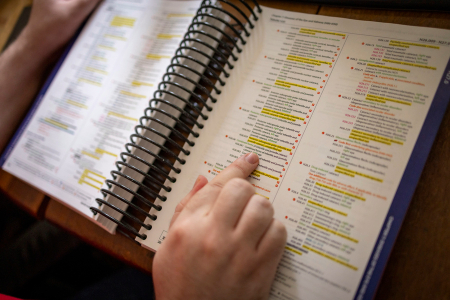 Book with yellow highlighted lines and hand pointing to section.