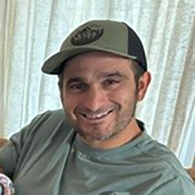 Man in green baseball hat smiling. 