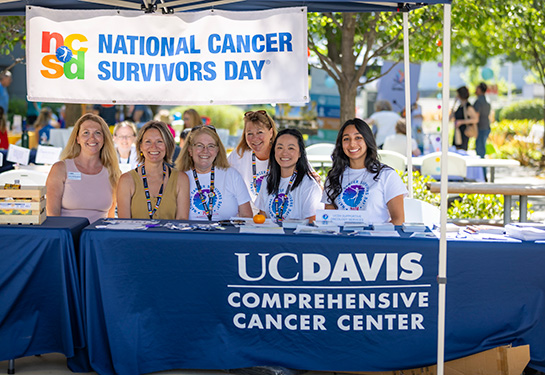 Group of women sitting behind table linen that says UC Davis Comprehensive Cancer Center