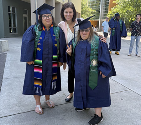 a professor with two students in caps and gowns
