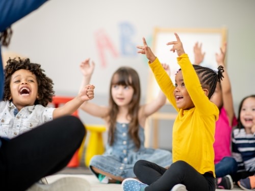 A group of children sit on the floor during a fun activity.