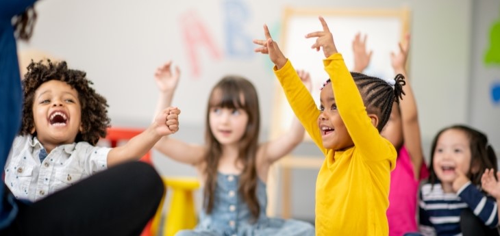 A group of children sit on the floor during a fun activity.