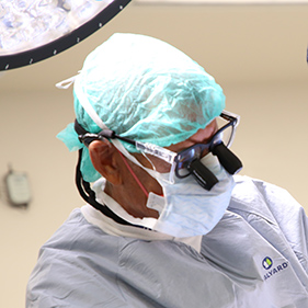 Doctor in scrubs, a mask and eyewear during a surgical procedure.