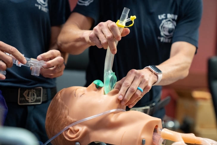 A hand is shown inserting an insert airway device on a mannequin. 