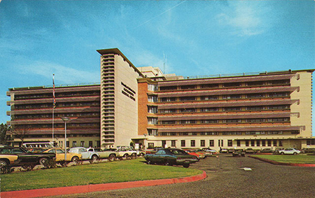 Photo the front of the North/South Tower with East Wing addition with cars in the parking lot.