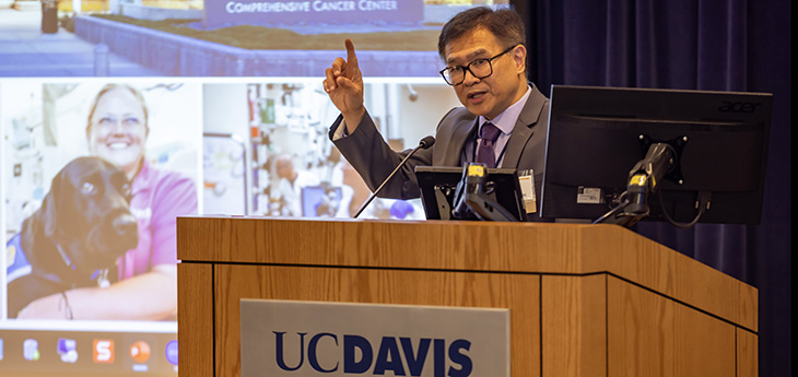 A middle aged man in a suit speaking at a podium in front of an audience.