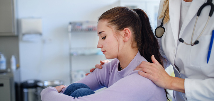 Doctor consoling unhappy teenage girl