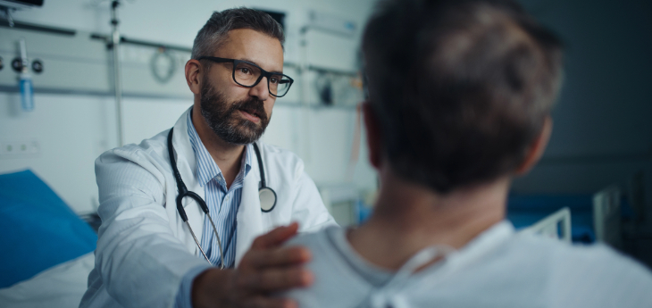 Doctor leaning forward with hand on patient's shoulder.