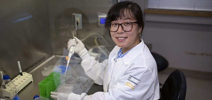 A researcher in a white coat works on experiments in a lab. 