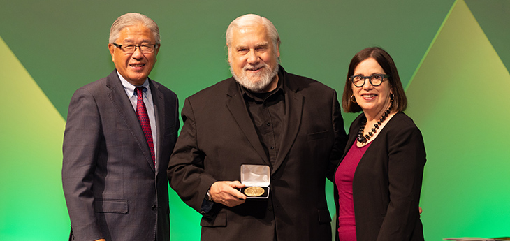 Kenneth W. Kizer is holding a medal in his hand and standing between Victor Dzau and Elena Fuentes-Afflick. 