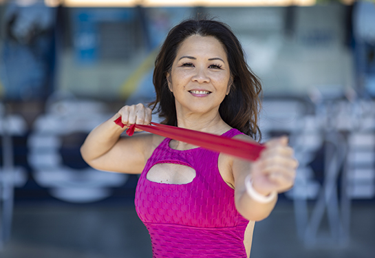 Mid-age women holding pink ribbon with both hands in fist