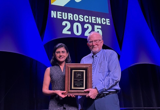 Female and male holding plaque award for neuroscience 2025
