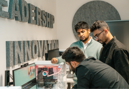Three people working on a project under a sign that reads Innovation.