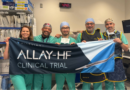 A medical team stands together in a procedure room holding an “ALLAY‑HF Clinical Trial” banner.