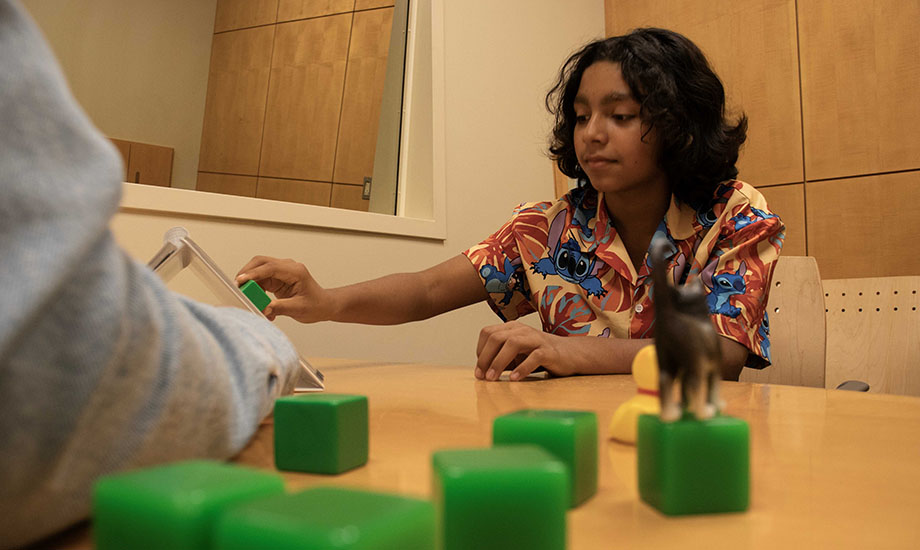 A young boy takes part in research at the UC Davis MIND Institute by putting blocks into a puzzle