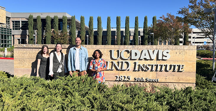 A young research participant poses for a photo with three members of a research team at the MIND Institute