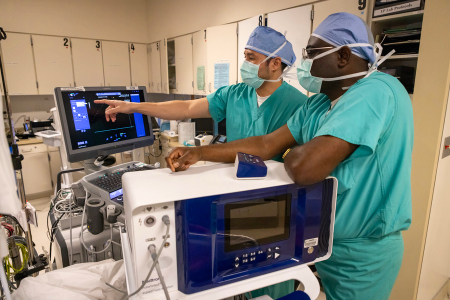 Two clinicians review and discuss information displayed on a medical monitor in an electrophysiology lab.