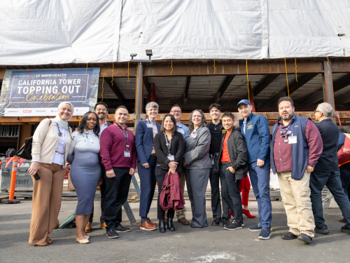 A group of UC Davis Health employees and project partners pose together at the California Tower construction site during a topping out ceremony.