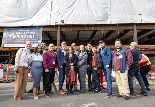 A group of UC Davis Health employees and project partners pose together at the California Tower construction site during a topping out ceremony.