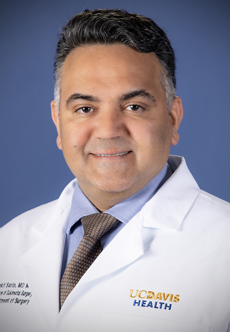 Man wearing white coat and smiling.