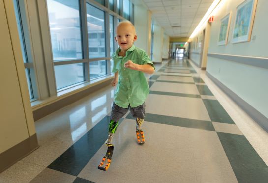 Boy with prosthetic legs runs in empty hospital corridor